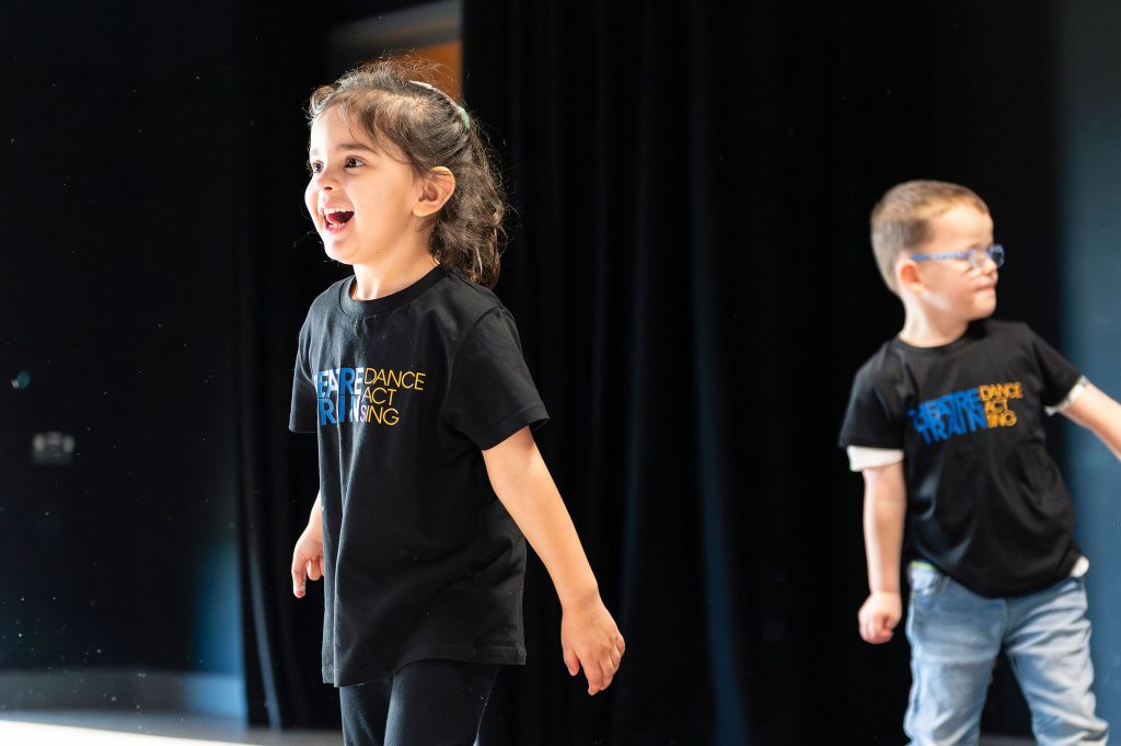 Young people taking part in a creative Theatretrain class, expressing themselves through acting, singing and dancing.