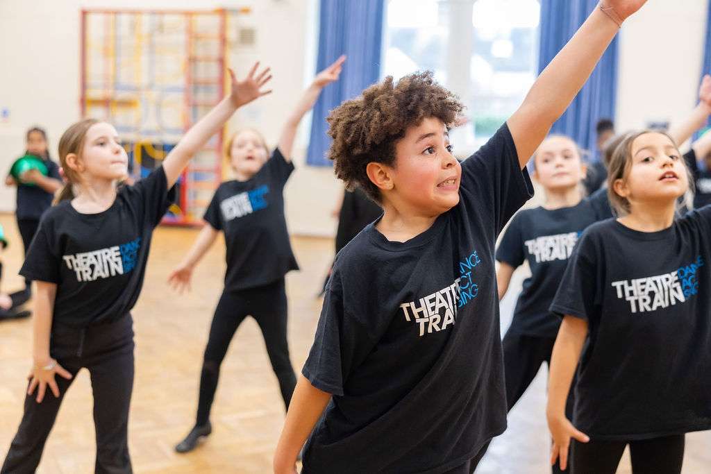 Young performers smiling and collaborating during performing arts classes at Theatretrain Maldon in Essex.
